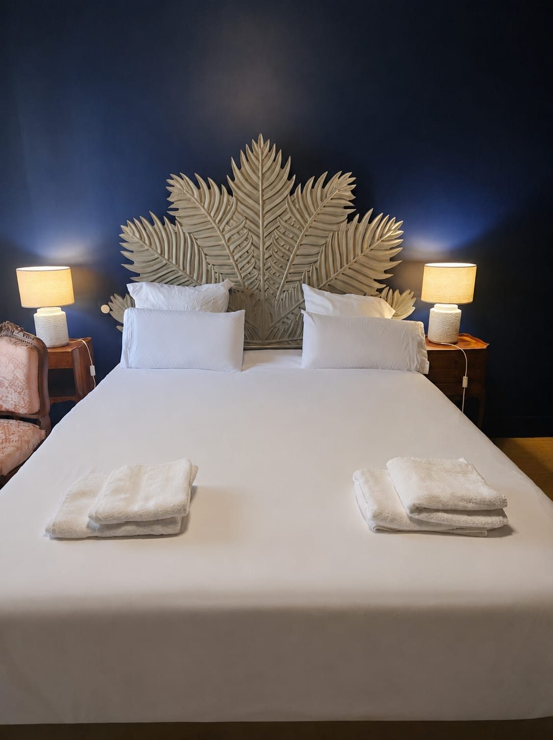 La Chambre Bleu Nuit — grand lit, serviettes moelleuses et spectaculaire tête de lit sculptée en feuilles de palmier sur mur bleu profond