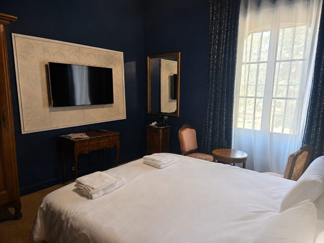Chambre Bleu Nuit — le coin télévision, miroir doré et haute fenêtre sur le parc