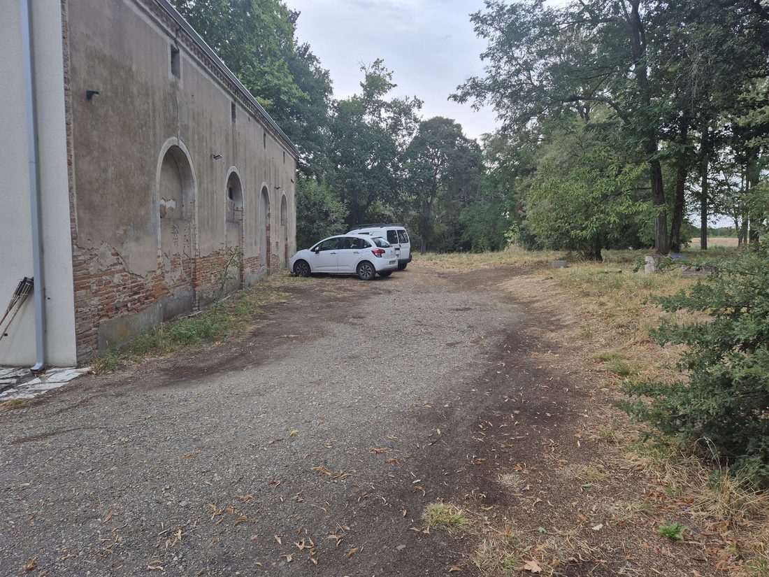 Le parking privé du domaine, vaste terrain le long des anciennes arcades — place pour les grands véhicules
